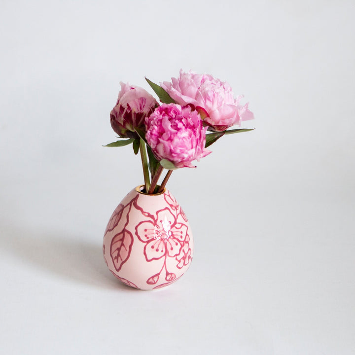 Pink chinoiserie bud vase holding a few fuchsia peonies on a pale gray backdrop, a sweet shower centerpiece