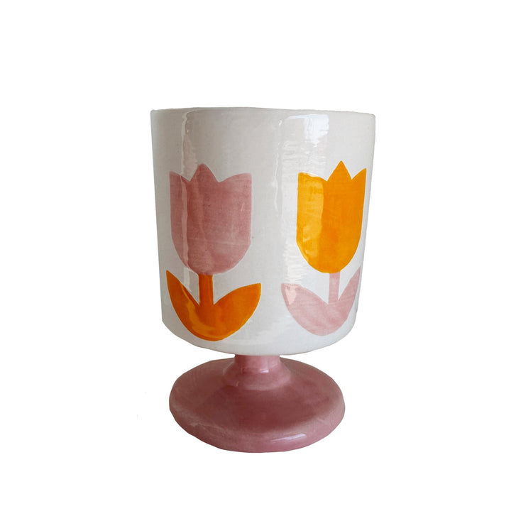 White ceramic tulip cup with pink and orange tulips on a pink pedestal base