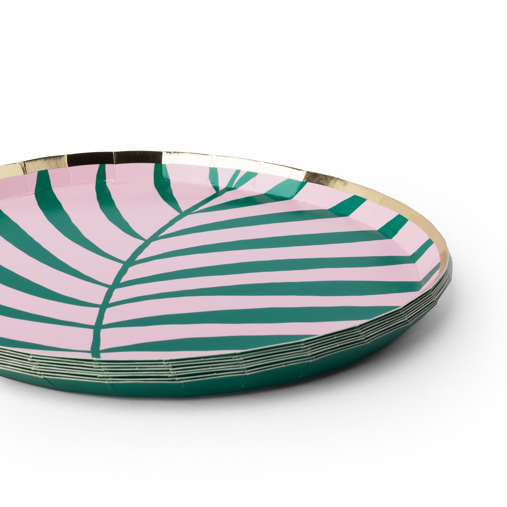 A stack of round paper plates featuring a pink and green palm leaf pattern with a metallic gold rim, shown on a clean white background.