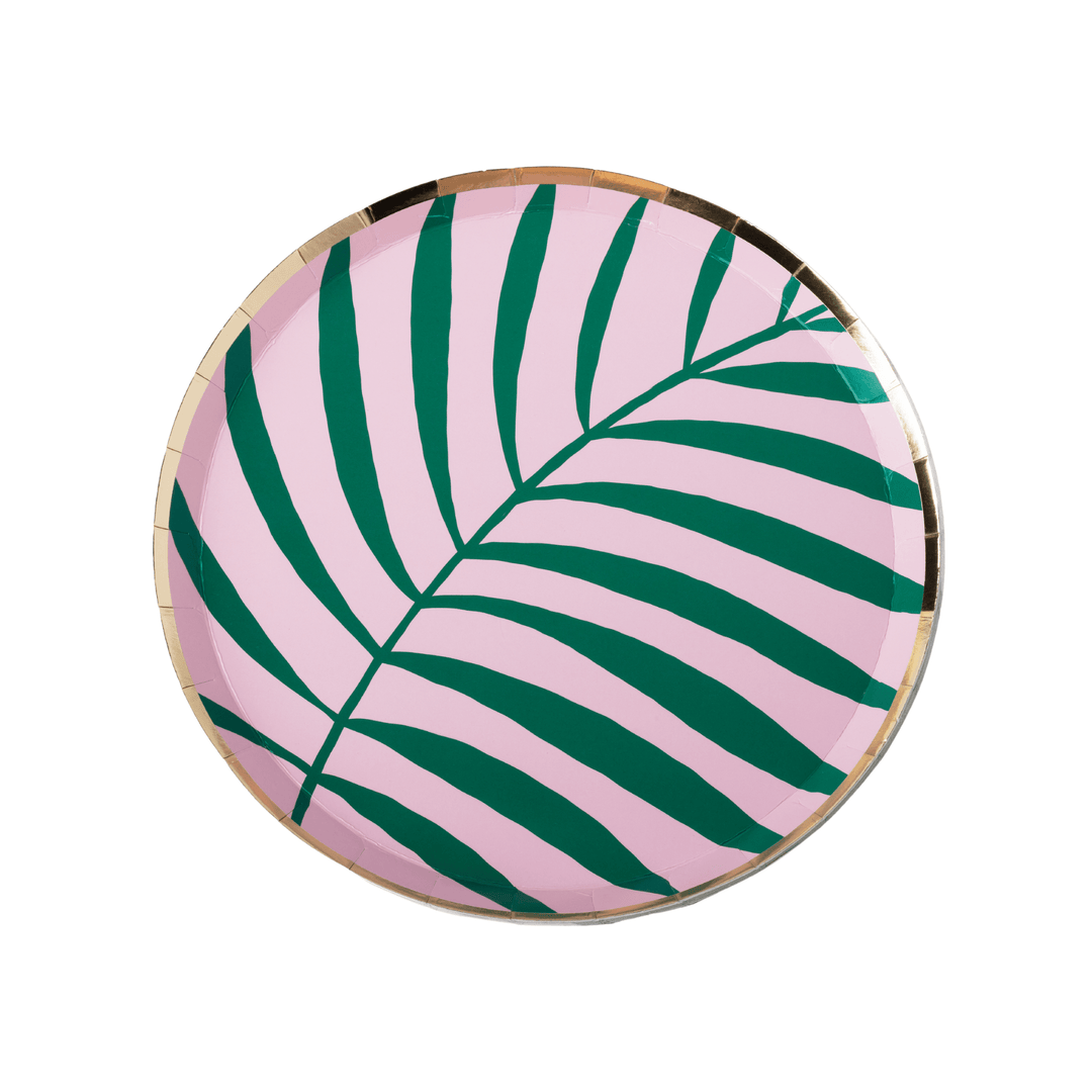 A round paper plate featuring a tropical palm leaf pattern in dark green on a light pink background, finished with a metallic gold rim.