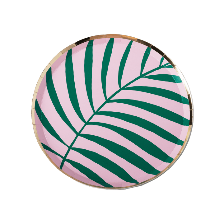A round paper plate featuring a tropical palm leaf pattern in dark green on a light pink background, finished with a metallic gold rim.