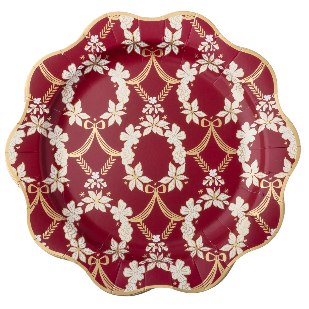 A scalloped paper plate with a deep red background and an elegant white and gold damask floral pattern, isolated on a white background.