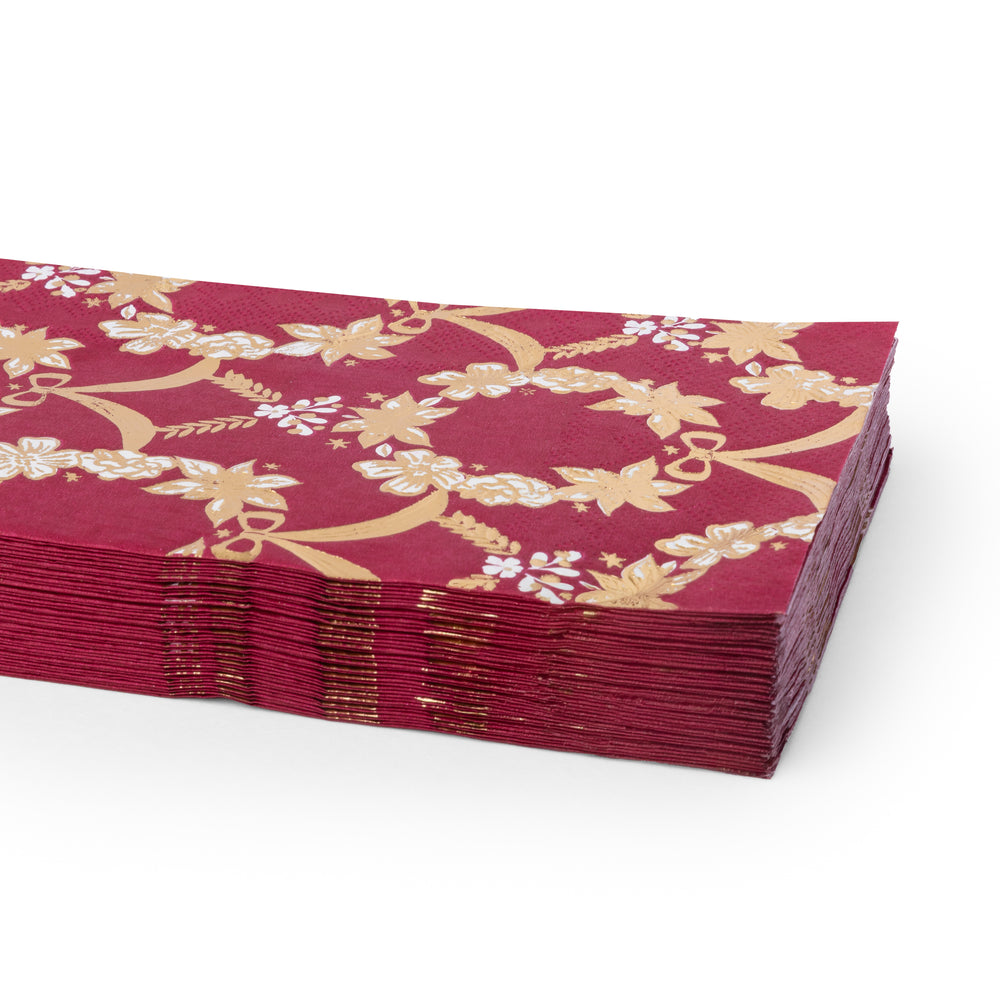 A stack of deep red paper napkins featuring a gold floral and vine pattern, with some white floral accents, shown on a clean white background.