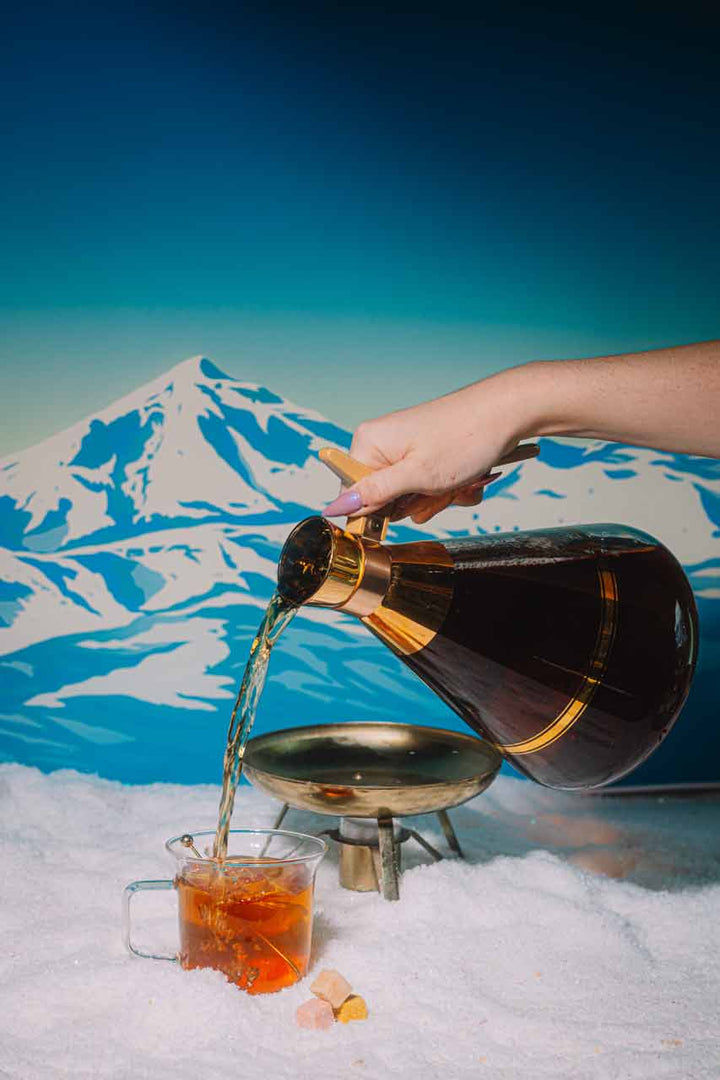 Hot toddy being poured into a mug on a winter table