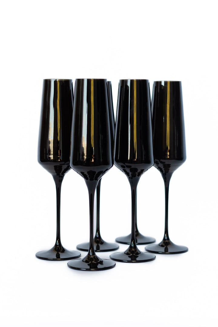 Four black champagne flutes with gold accents on a white background