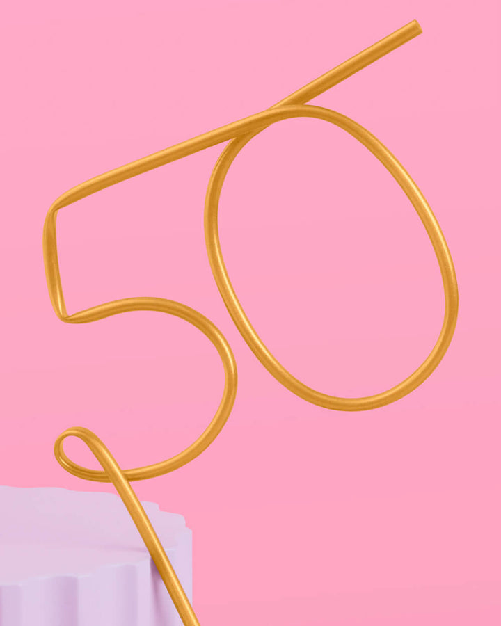 Gold 50th birthday straw beside a lavender pedestal