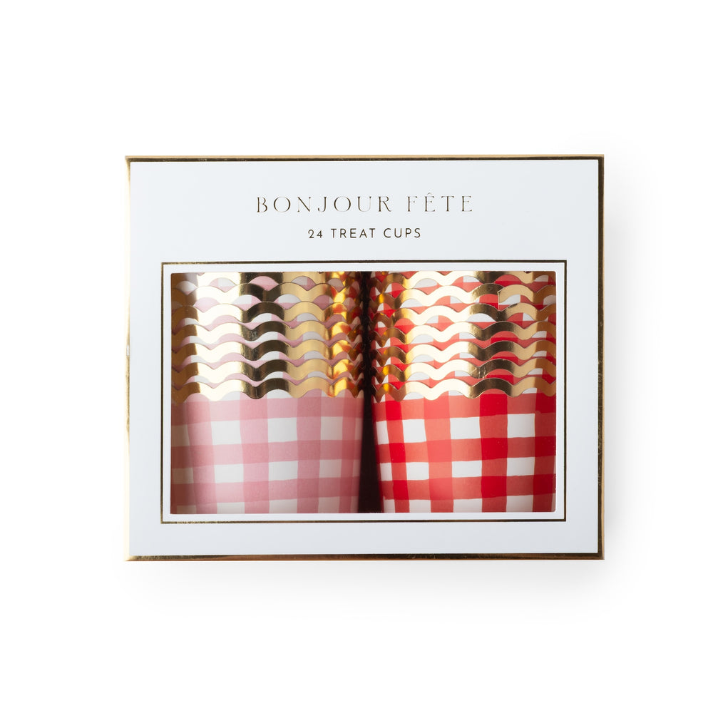 A boxed set of 24 treat cups with the text 'BONJOUR FÉTE' and '24 TREAT CUPS' on a white package with a gold border. The cups visible through the window include pink and red gingham patterns with metallic rose gold, gold, and silver wavy designs.