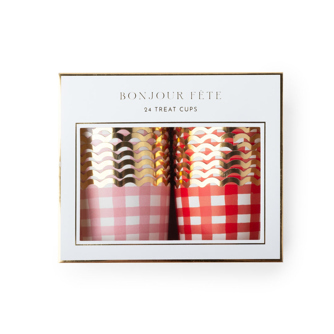 A boxed set of 24 treat cups with the text 'BONJOUR FÉTE' and '24 TREAT CUPS' on a white package with a gold border. The cups visible through the window include pink and red gingham patterns with metallic rose gold, gold, and silver wavy designs.