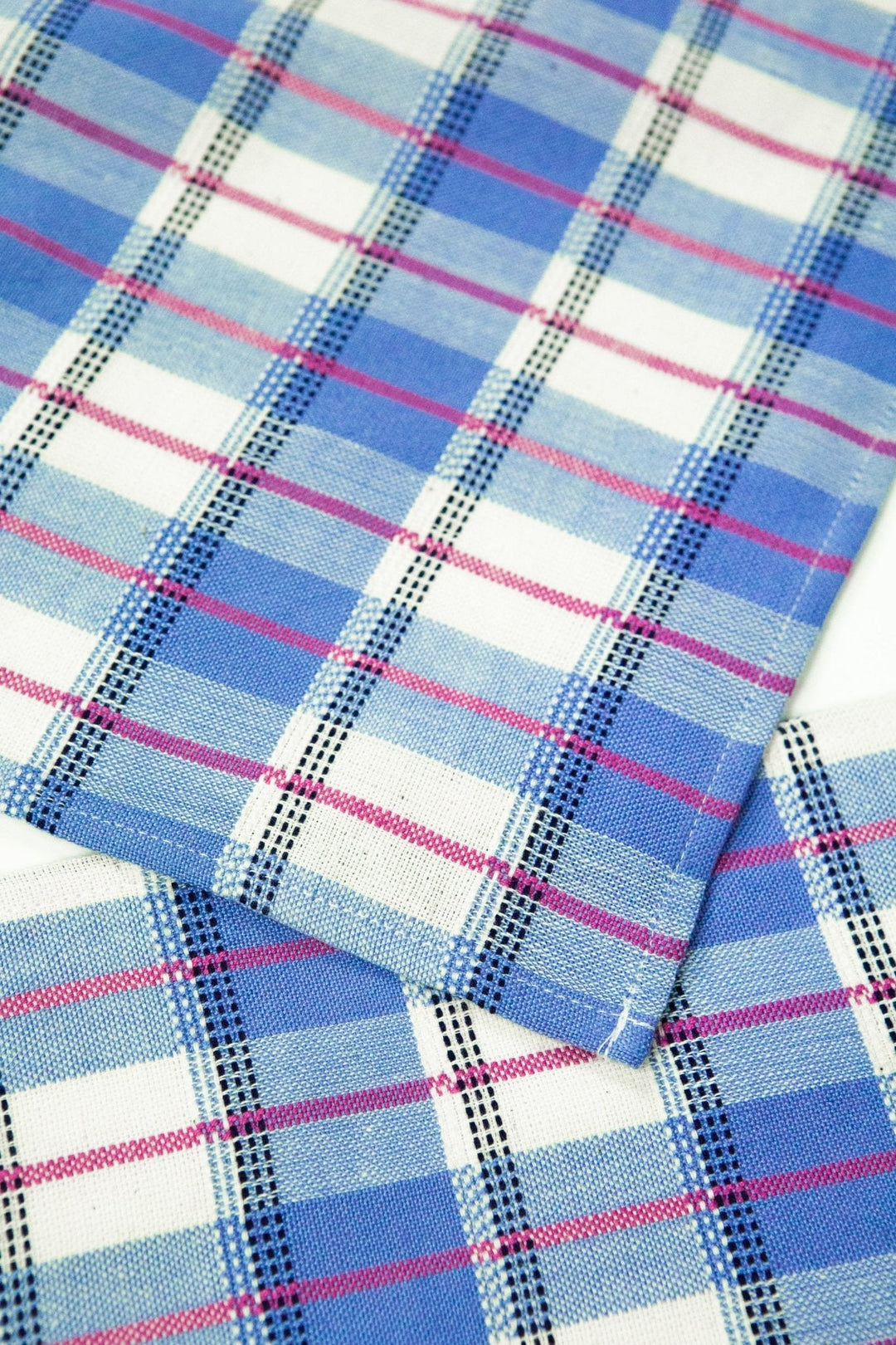 Close-up of blue and white gingham handwoven cotton weave with hot pink detail