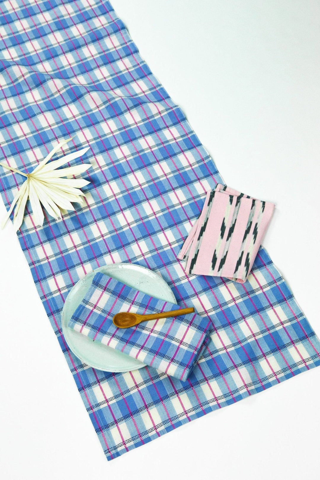 Blue and white gingham table runner with hot pink and navy accents styled on a dining table