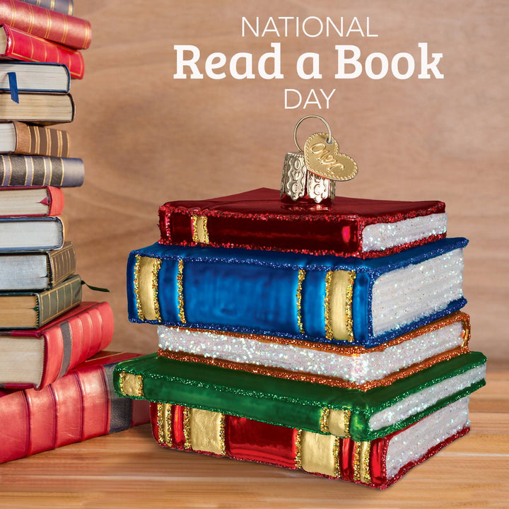 Book ornament set on a wooden table beside real hardcover books under a National Read a Book Day headline