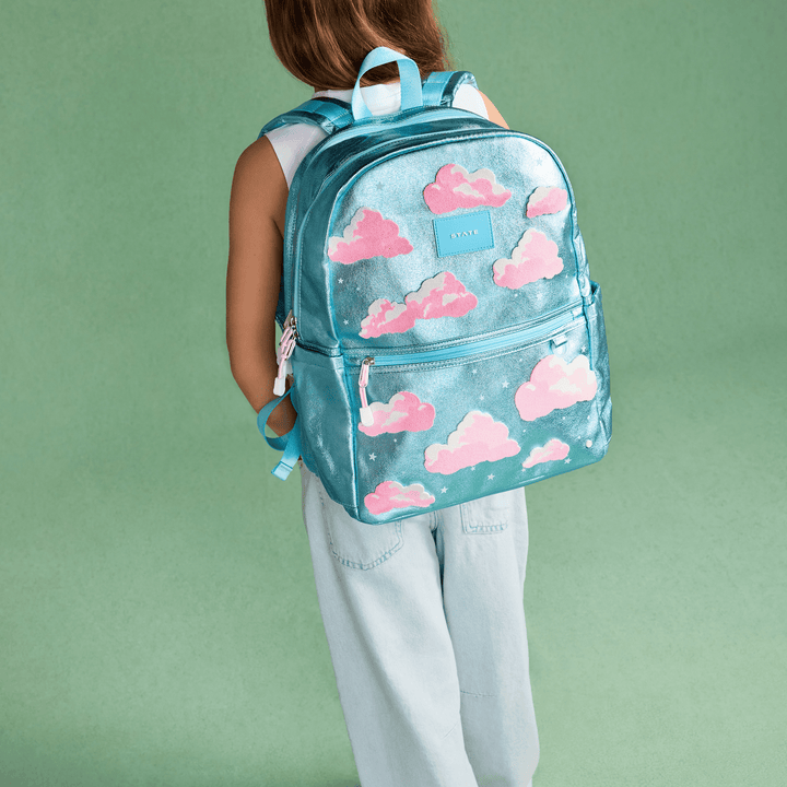 Child wearing the Clouds backpack against a green backdrop