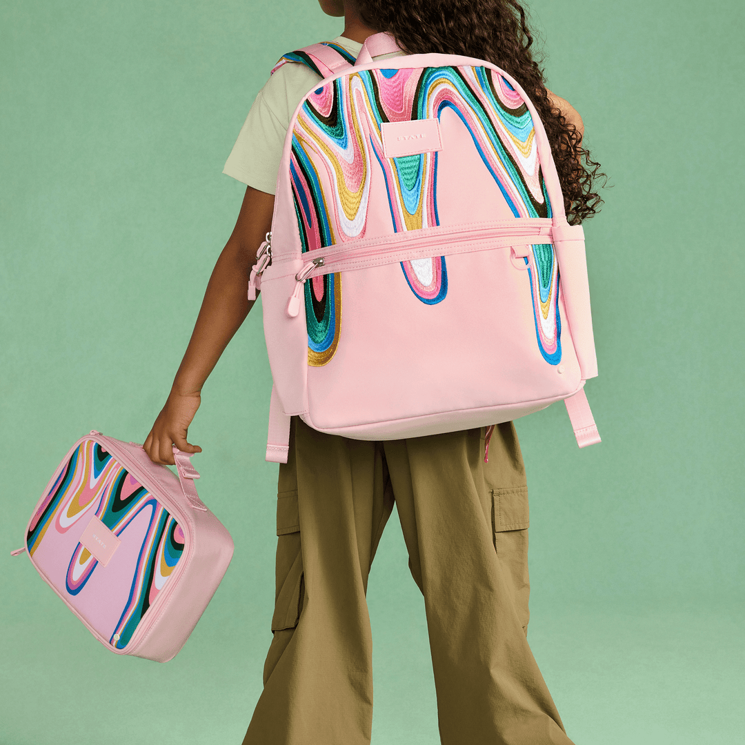 Child wearing the Paint Wave STATE Kane backpack and carrying the matching lunch box
