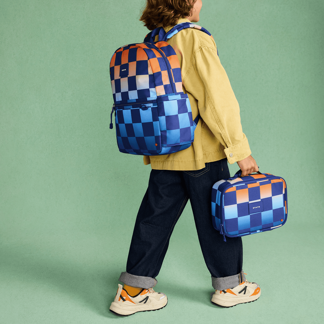 Child walking with the matching checkerboard backpack on and the Rodgers lunch box in hand