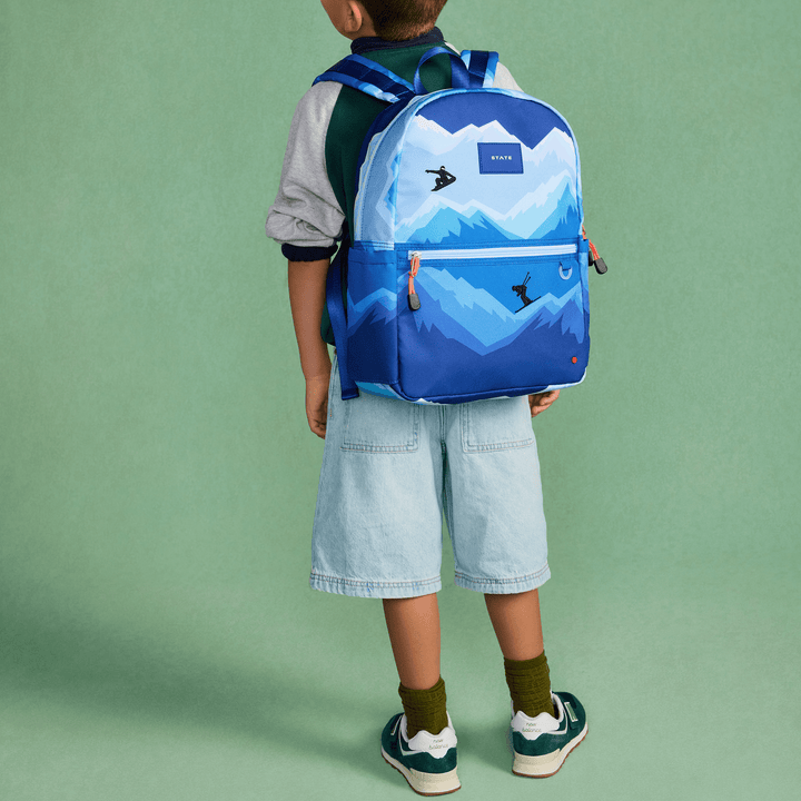 Boy seen from behind wearing the blue Mountains STATE Kane backpack