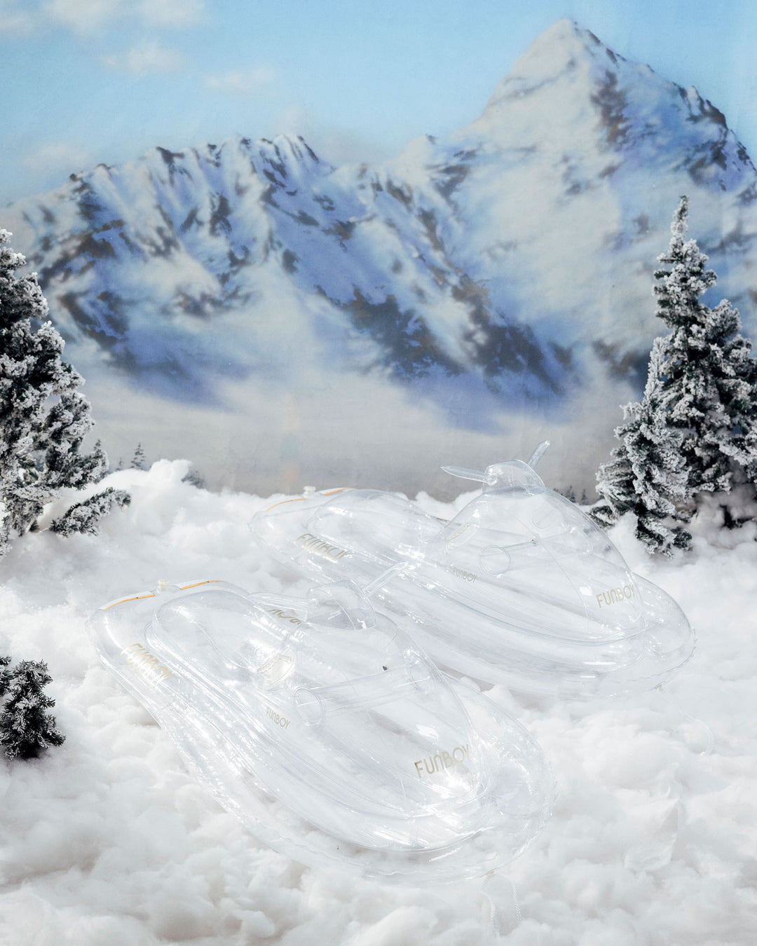 Couple riding a clear inflatable snowmobile sled on a snowy slope