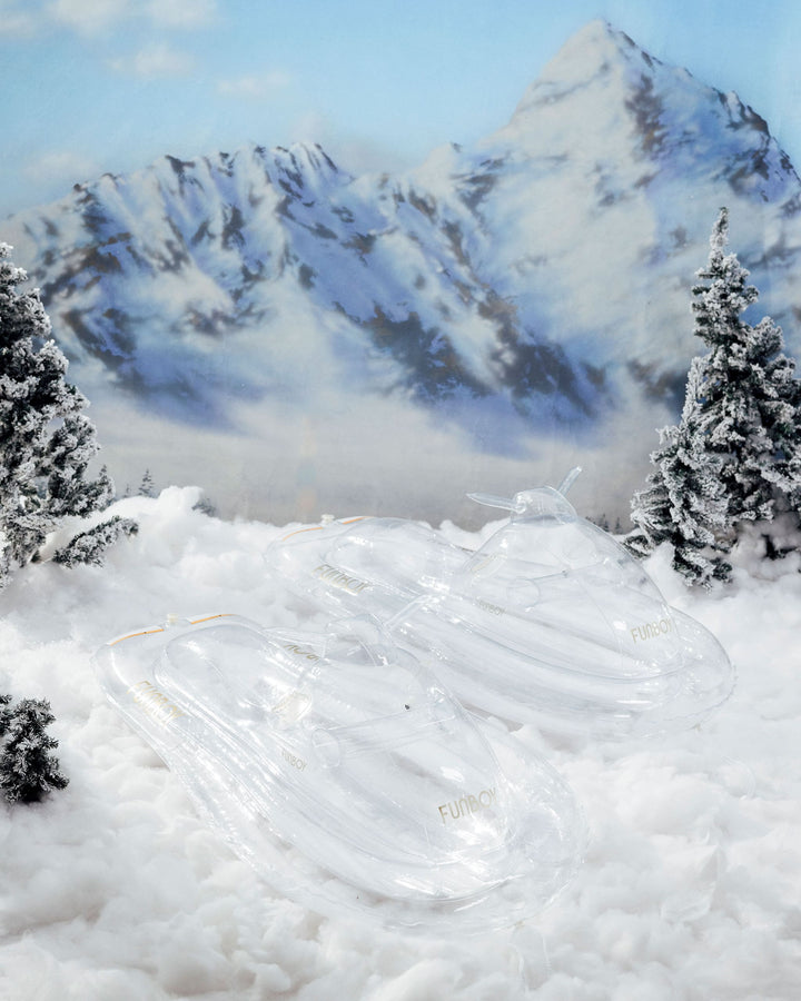 Couple riding a clear inflatable snowmobile sled on a snowy slope