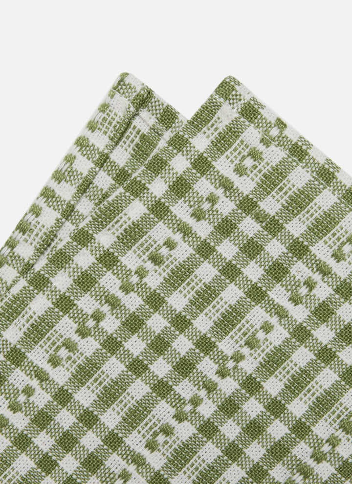 A close-up of folded fabric with a woven green and white check pattern on a light gray background.