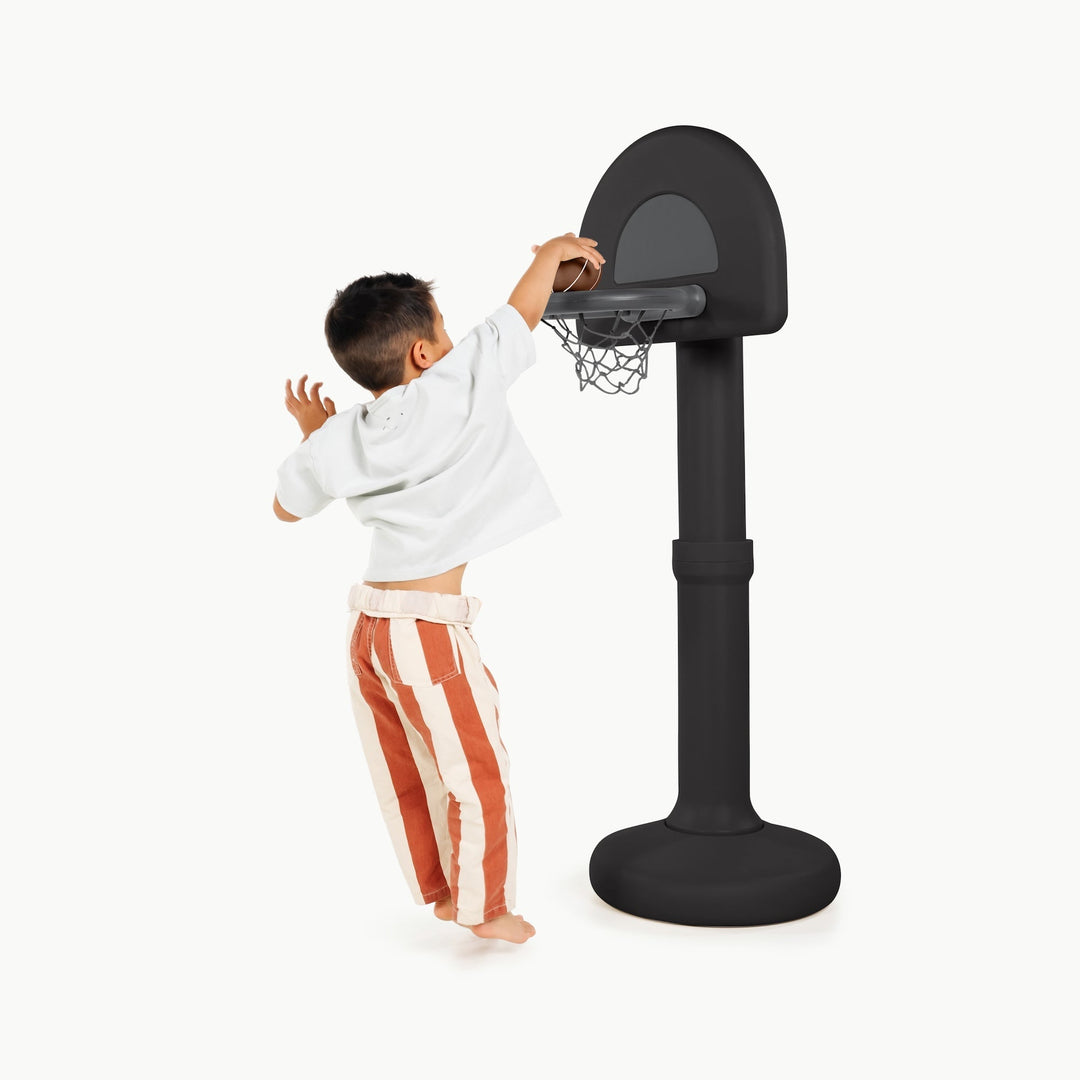 Boy in striped pants dunking a ball at the raven black toddler basketball hoop