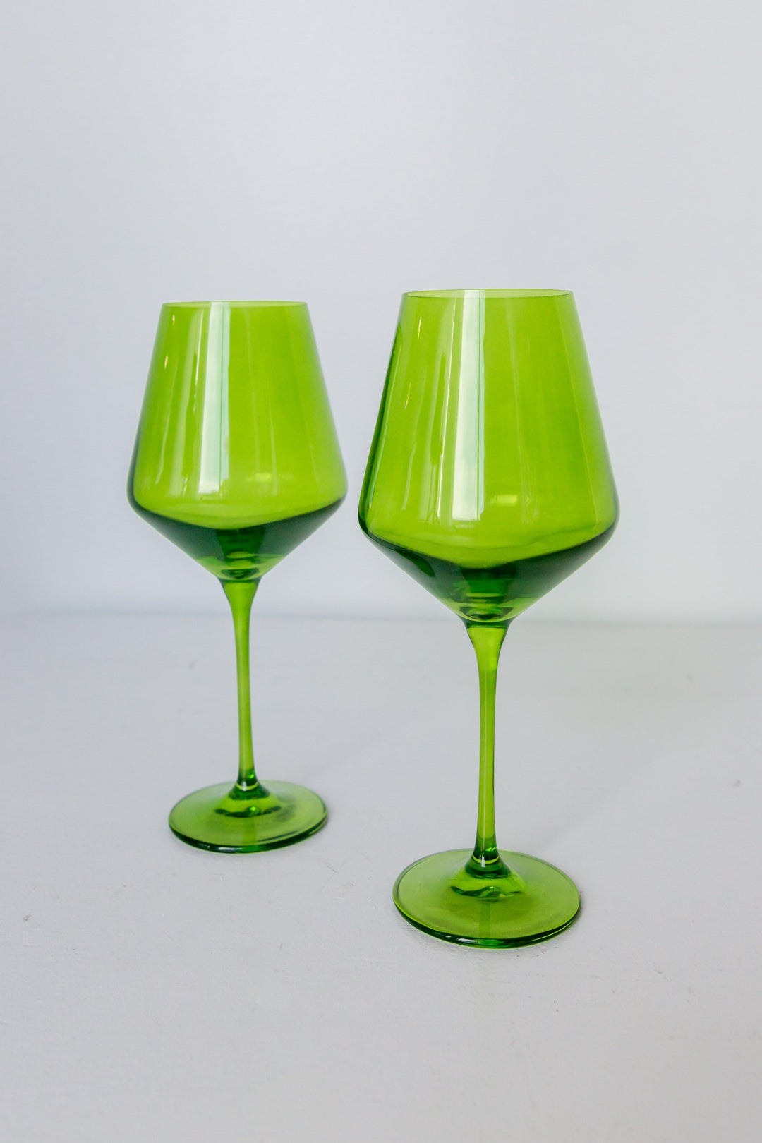Two green wine glasses on a light gray background
