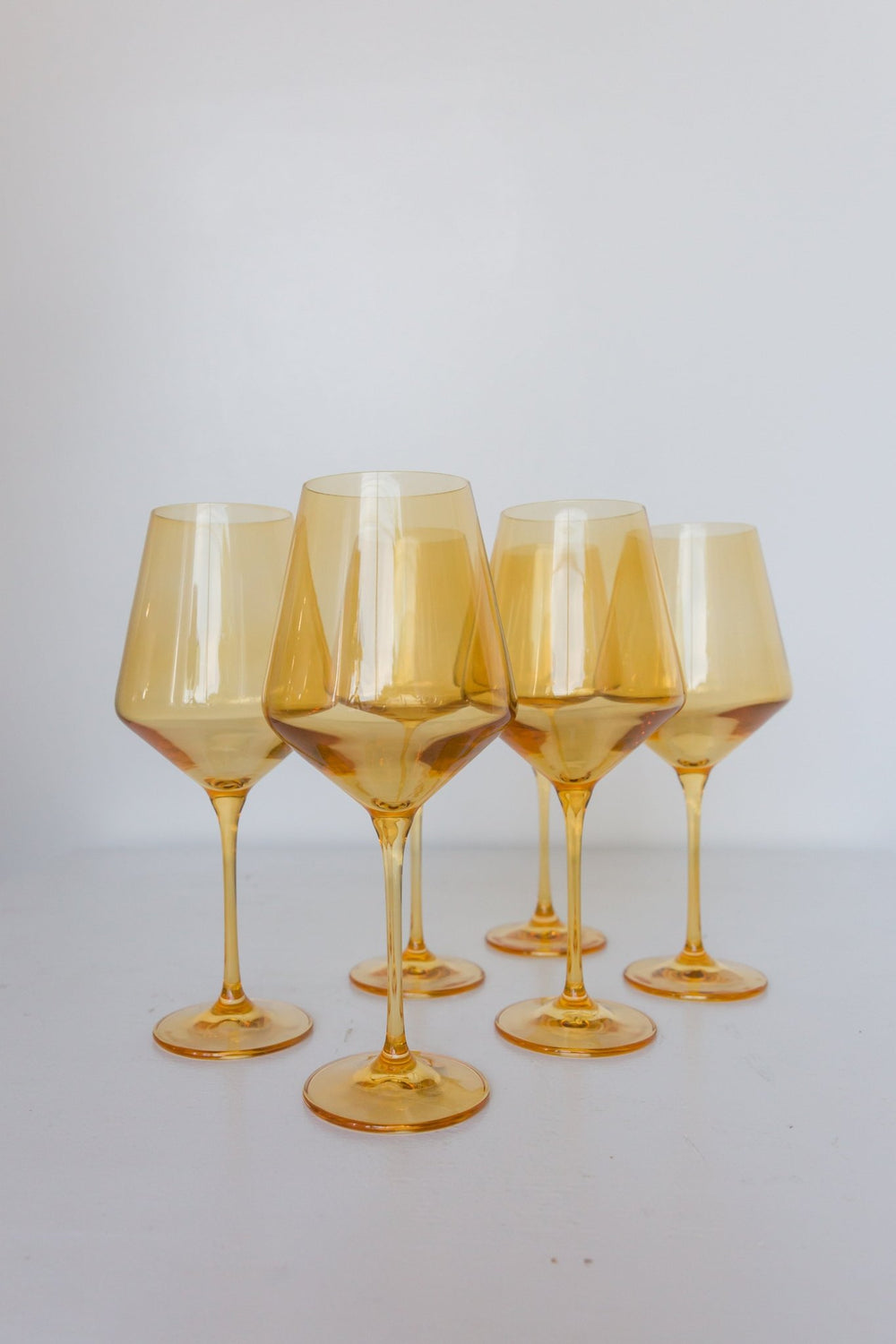 Estelle yellow colored glass wine glasses standing together on white, for a celebration table
