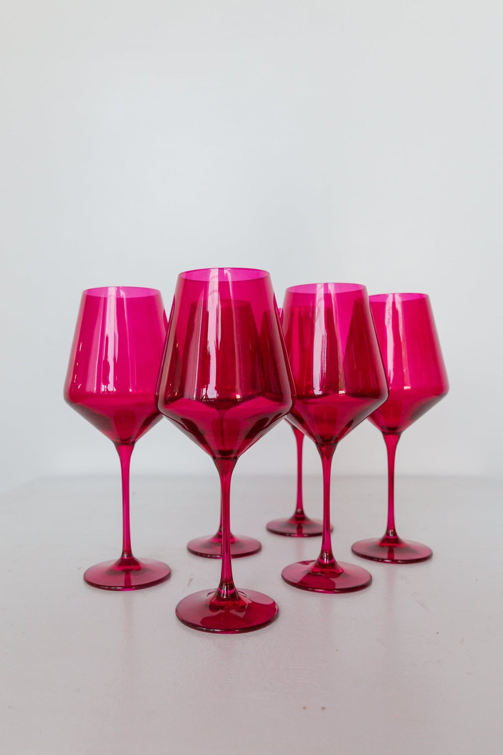 Estelle fuchsia colored glass wine glasses grouped on a pale grey backdrop, for a celebration table