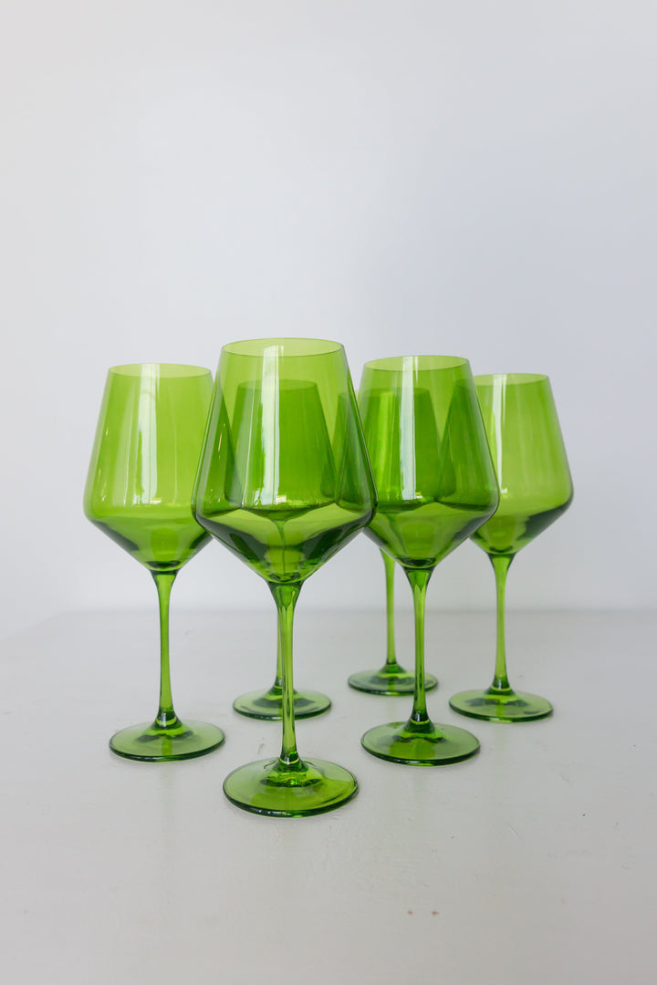 Five green wine glasses on a white background