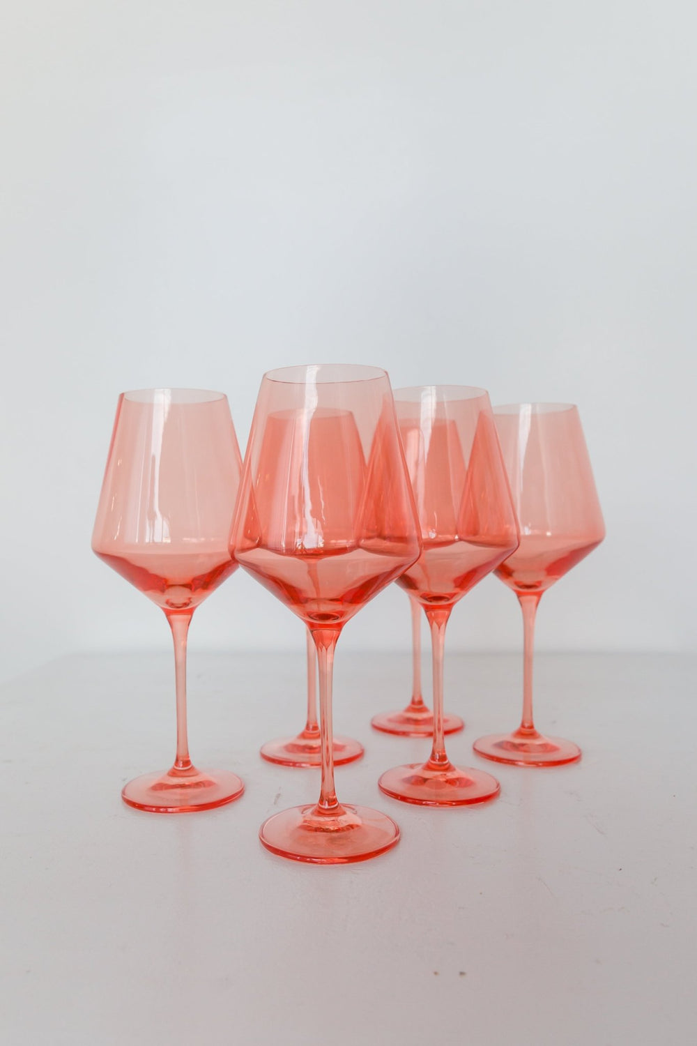 Estelle coral peach colored glass wine glasses standing together on white, for a celebration table
