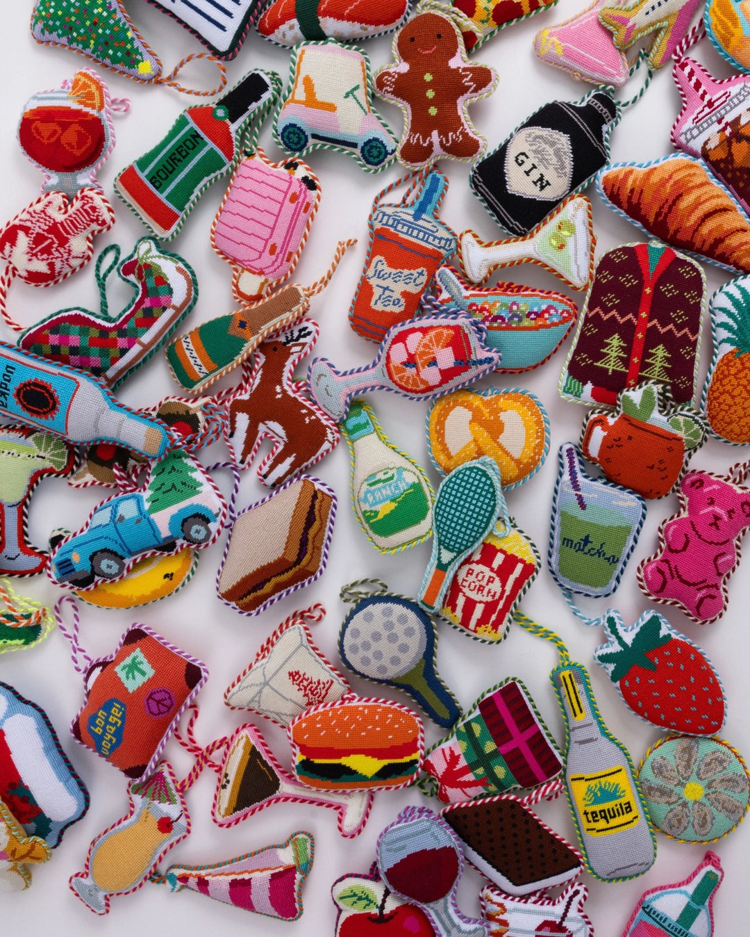 Flat lay of dozens of Furbish needlepoint icon ornaments, the tennis racket near the center