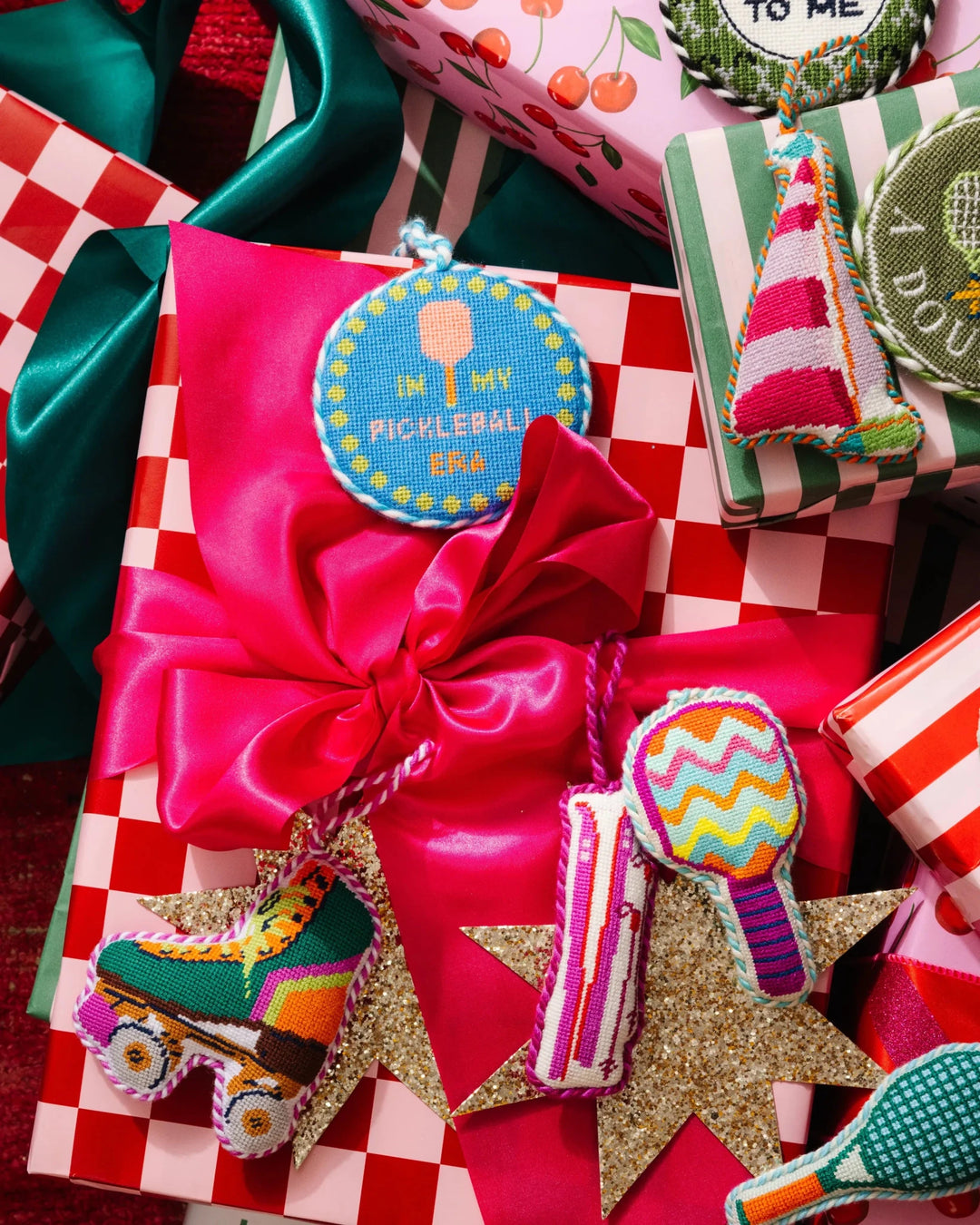 Roller skate ornament tied to a pink satin wrapped gift beside a pickleball paddle ornament