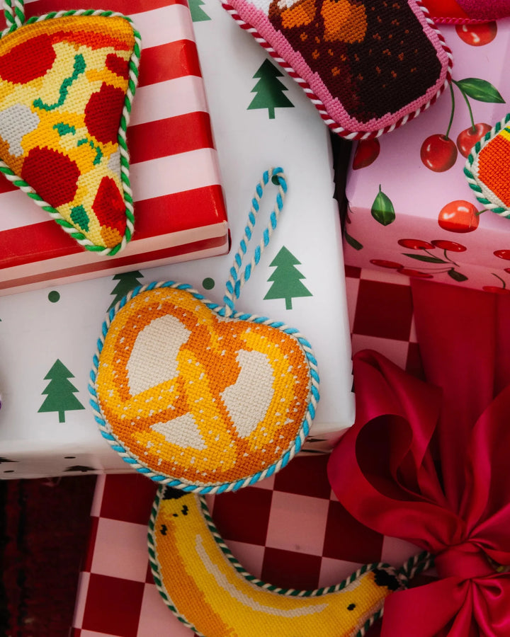 Pretzel ornament on red checkered and Christmas tree print gifts with pizza and banana ornaments