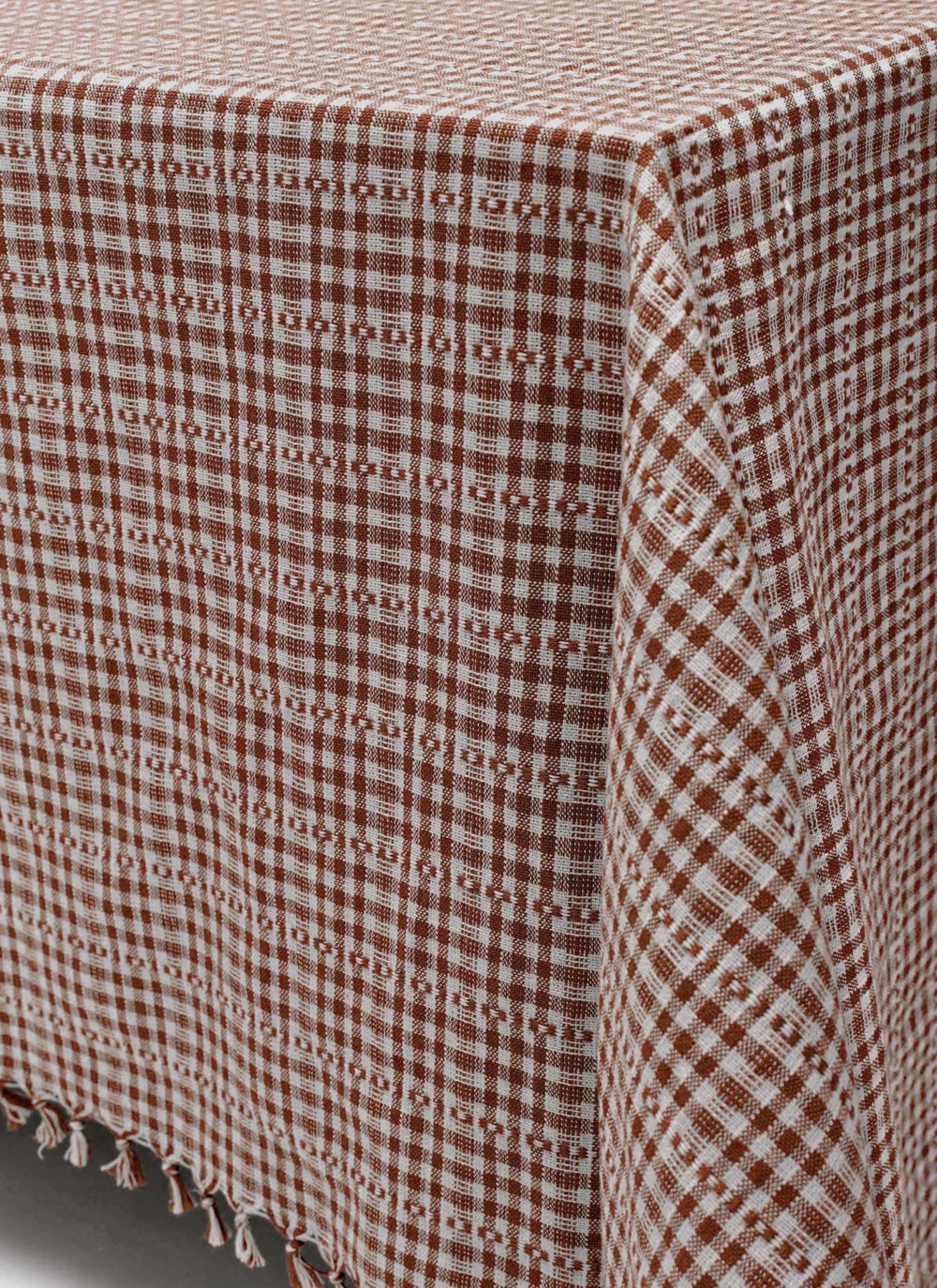 Nutmeg check tablecloth draped over a table corner showing the tassel trimmed hem