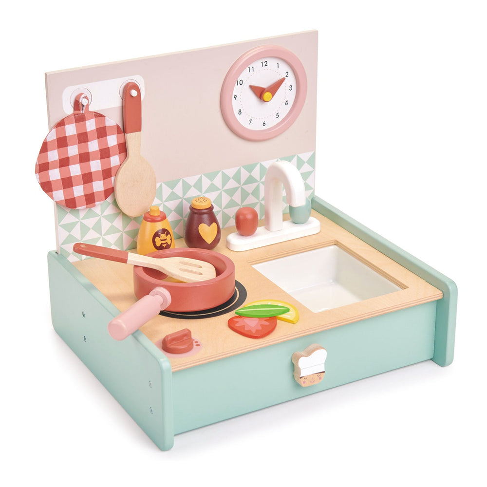 Angled view of the tabletop play kitchen with a frying pan on the hob, wooden tap, and honey and chocolate pots