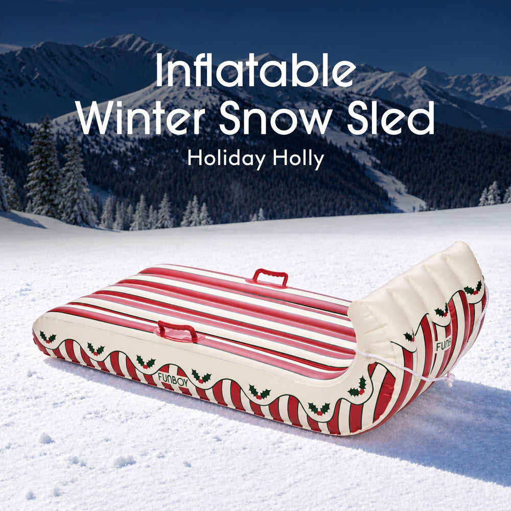 Holly stripe inflatable Christmas toboggan sled on a snowy hillside