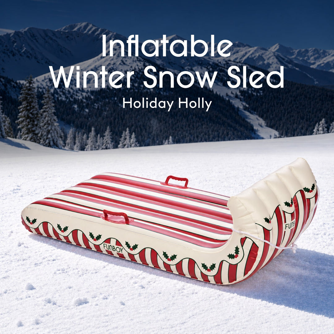 Holly stripe inflatable Christmas toboggan sled on a snowy hillside