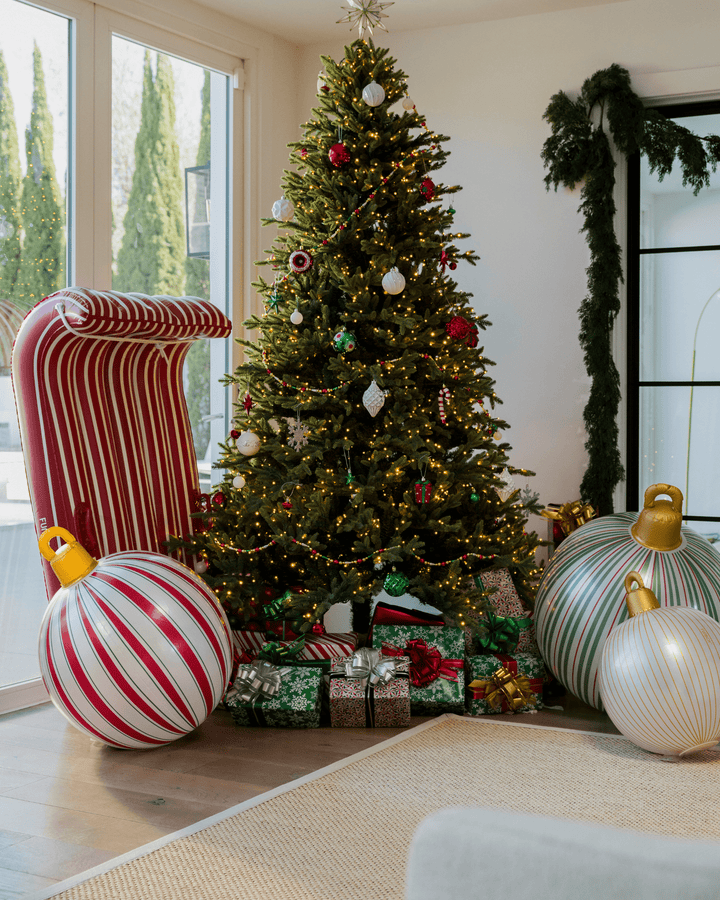 Red and white striped inflatable sled as holiday decor beside a decorated Christmas tree