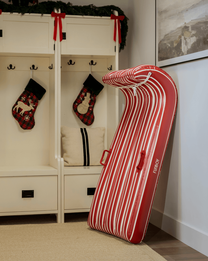 Red and white inflatable toboggan leaning in an entryway with Christmas stockings