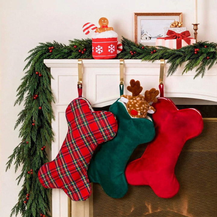 Garland mantel hung with tartan, green velvet, and cranberry velvet dog stockings