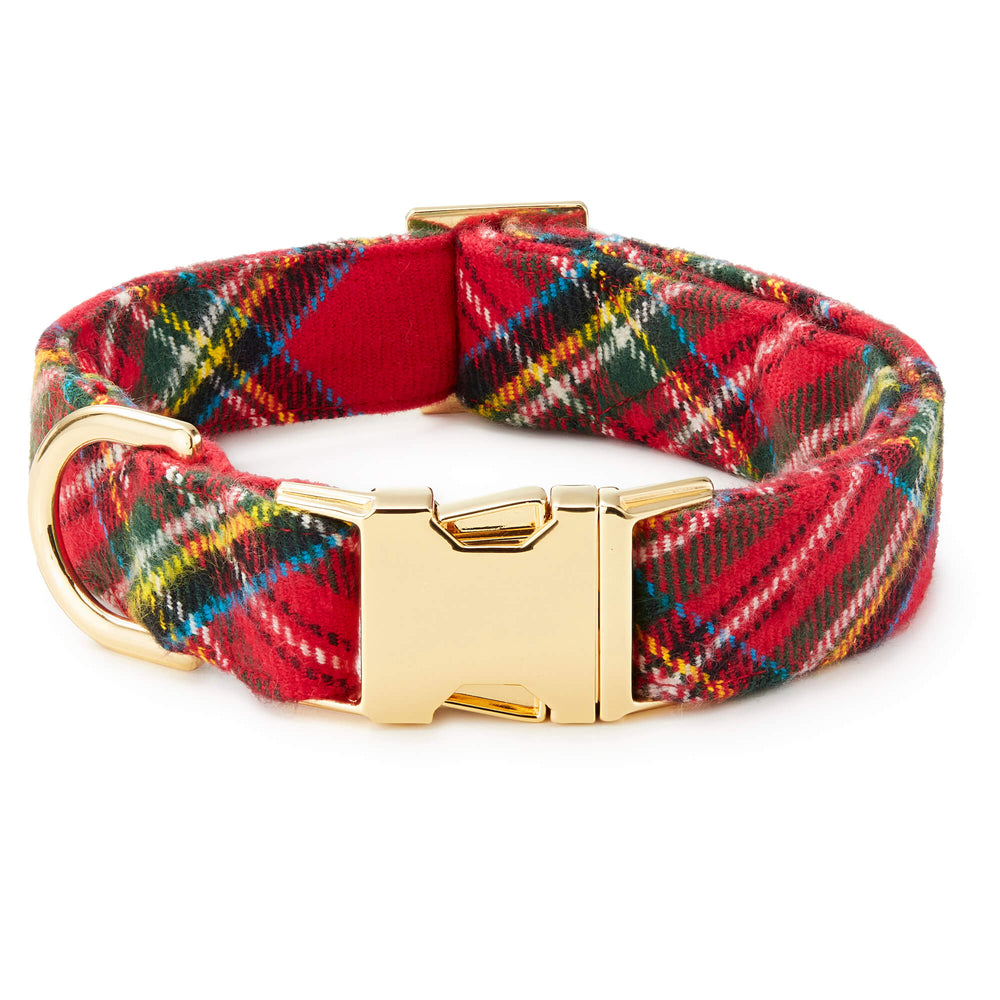Red tartan dog collar rolled into a circle, showing its polished gold buckle and D-ring.