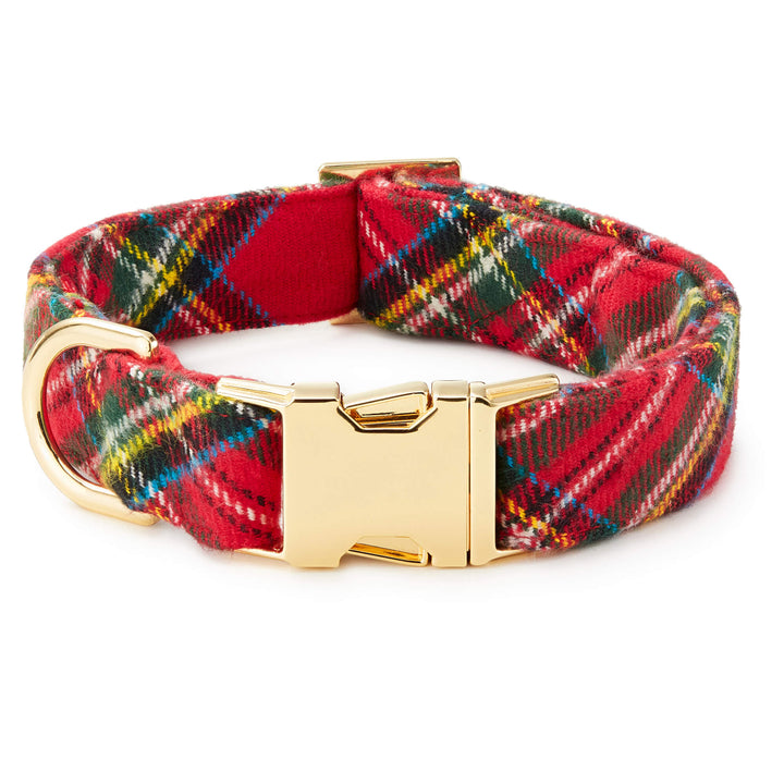 Red tartan dog collar rolled into a circle, showing its polished gold buckle and D-ring.