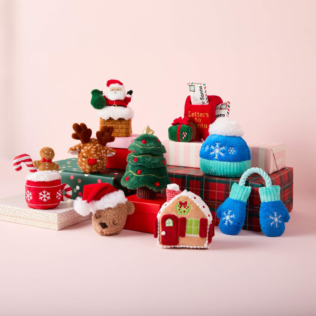 Holiday dog toy lineup on blush with the reindeer, Santa chimney, and mailbox on the top steps