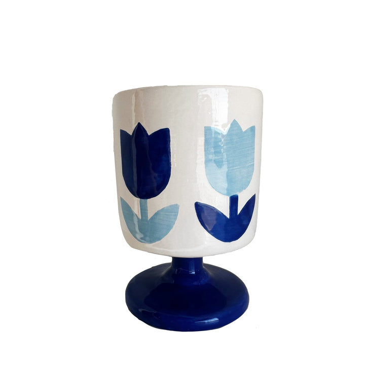 White ceramic tulip cup with navy and light blue tulips on a cobalt blue pedestal base