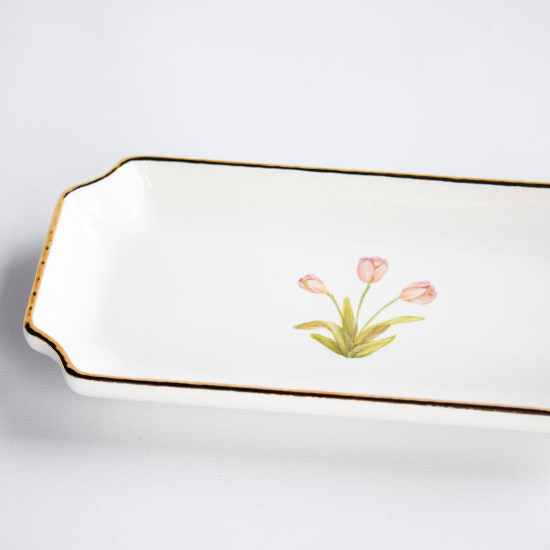 Angled close-up of the pink tulip motif and thin gold rim on the white petite valet tray