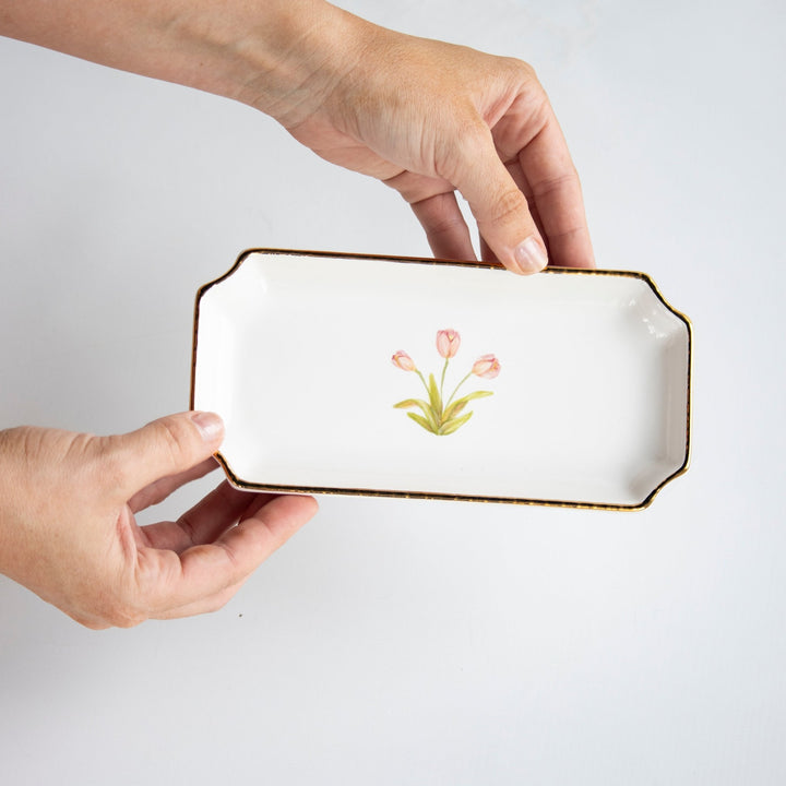 Hands holding the white tulip petite valet tray to show its size and gold edge