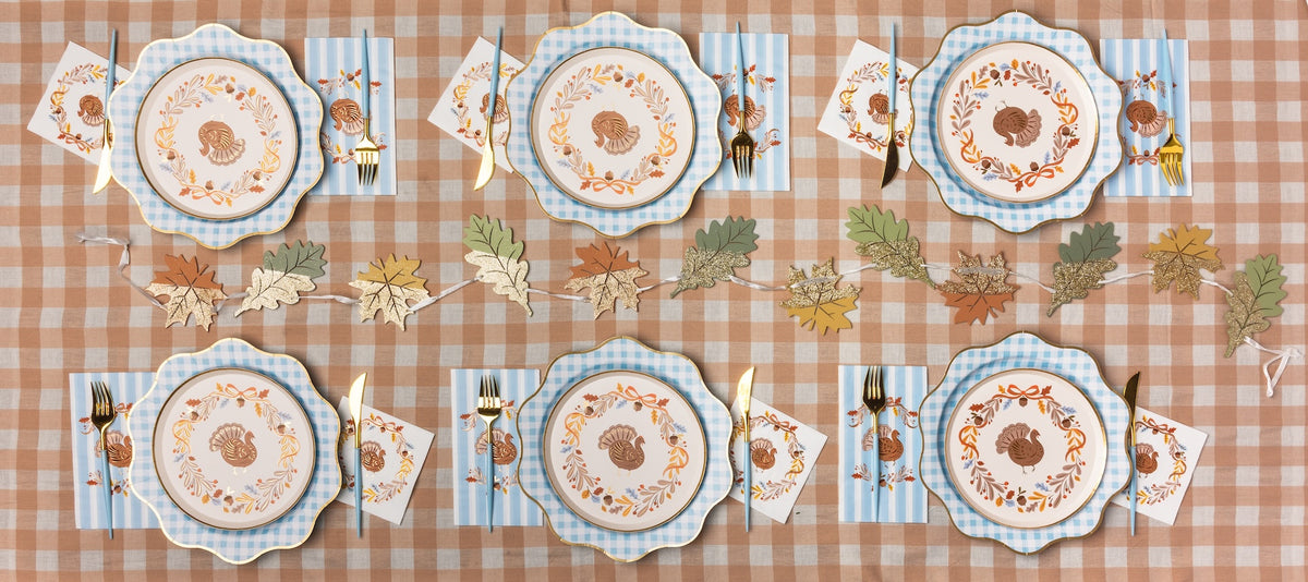 A styled table setting featuring gingham party supplies and Thanksgiving plates, napkins, and Thanksgiving party decorations.