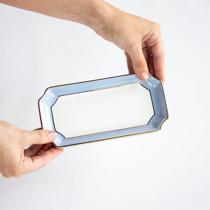 Hands holding a French blue petite valet tray to show its scale and gold edge, a thoughtful birthday gift