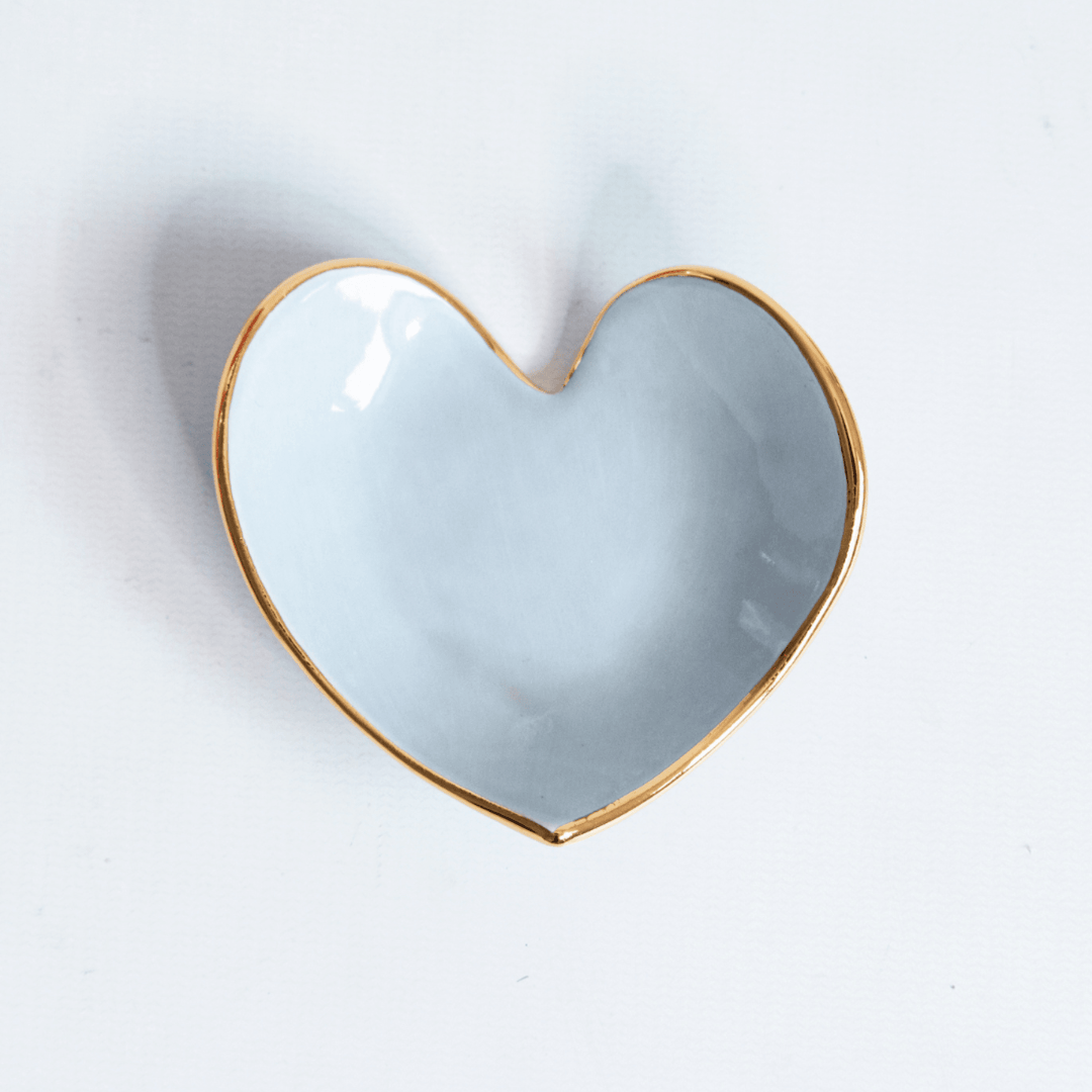 Powder blue heart ring dish with a gold rim, top view on white