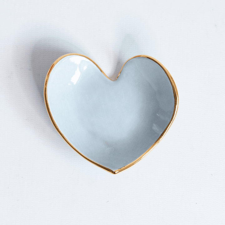 Powder blue heart ring dish with a gold rim, top view on white