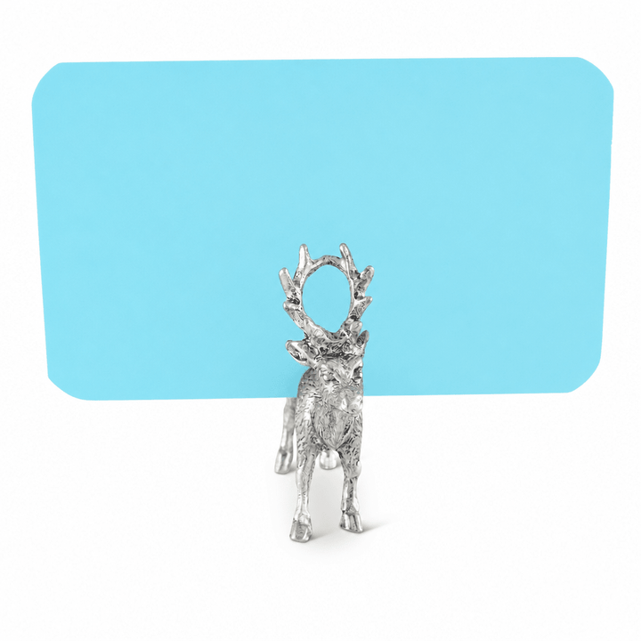 Pewter deer place card holder holding a blank blue card in its antlers on a white background