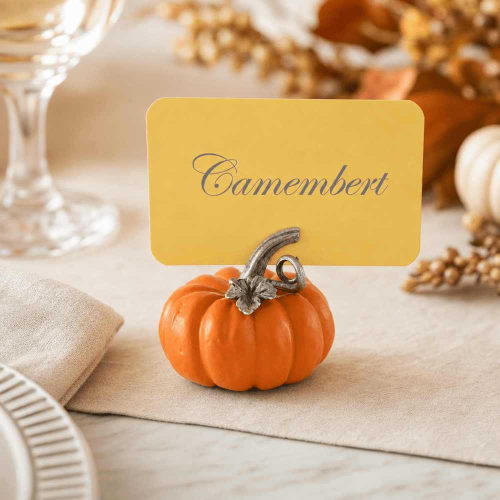 Pumpkin place card holder labeling Camembert on a fall table with gourds and a crystal glass
